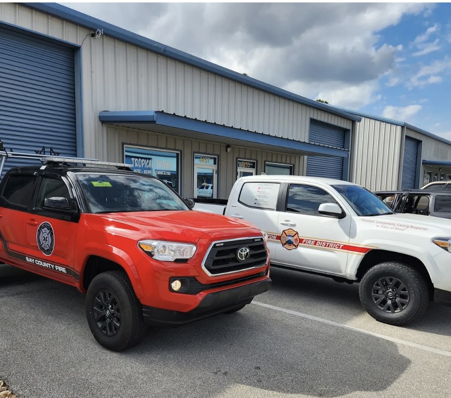 Red and white Toyota Tacoma fire department vehicles parked in front of industrial building